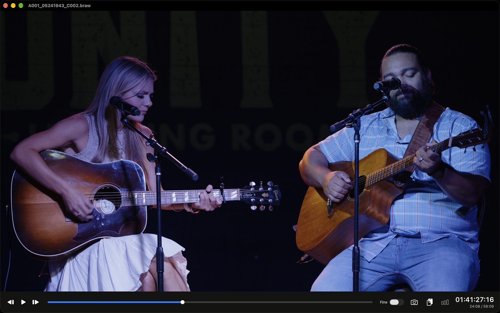 The same Blackmagic RAW frame with a look applied: full contrast, the stage lighting blue and the guitars warm